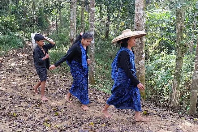 Dua orang perempuan dan seorang anak laki-laki dari Badui luar berjalan dengan mengenakan pakaian adat badui bercorak biru